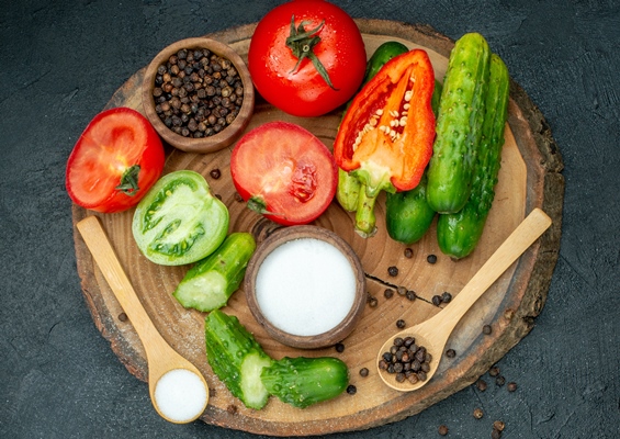 top view fresh vegetables chopped cucumber black pepper and salt in wooden spoon on wood board on dark background - Картофель, запечённый в фольге