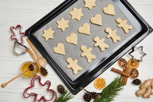 top view of laid out gingerbread cookies on pastry rack cookies cutter honey pine scones and branches dried slices of orange on wooden surface cooking process christmas preparations 25 december - Постные имбирные человечки