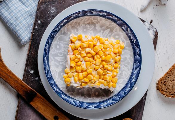 top view of mimosa salad with corn on the top on a wooden cutting board 1 - Постный салат "Мимоза" с морской капустой