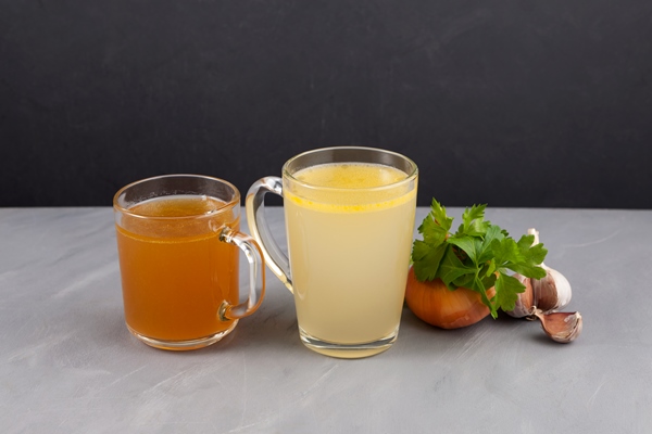 two types of bone broth yellow and brown in transparent cups fish and meat broth contain healthy collagen - Заливное из морепродуктов