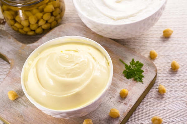 vegan mayonnaise made from chickpeas and legemus with a jar of aquafaba in the background egg or milkfree ingredient - Постный майонез с тофу