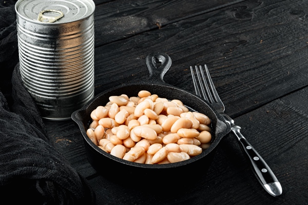 white canned beans set with metal can in cast iron frying pan on black wooden table background with copy space for - Постное пюре из фасоли и баклажанов