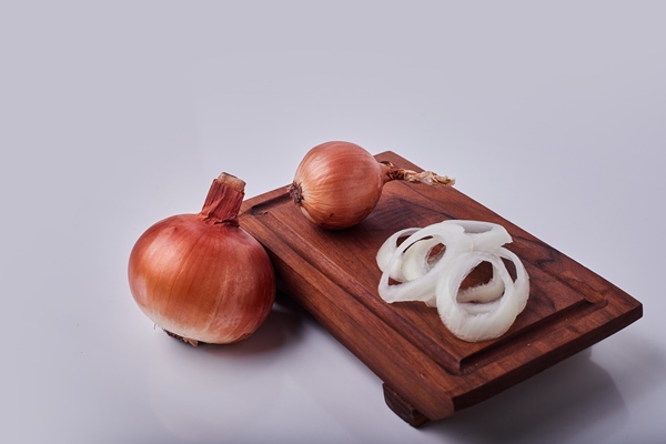 whole and sliced onions on a wooden board - Пирожки из слоёного теста постные