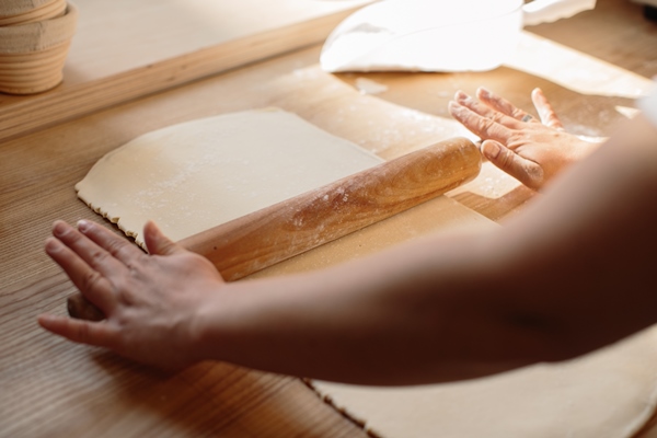 woman hands rolling out dough in flour with rolling pin in bakery - Пахлава