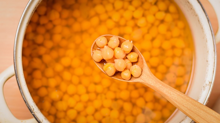 wooden spoon with boiled chickpeas over a pan - Салат из нута со сладким перцем