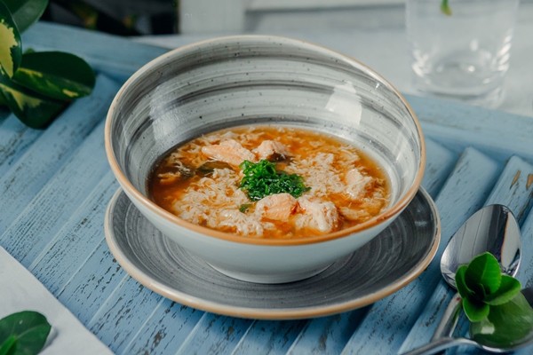 a bowl of hot soup with diced green onion in modern bowl - Рассольник
