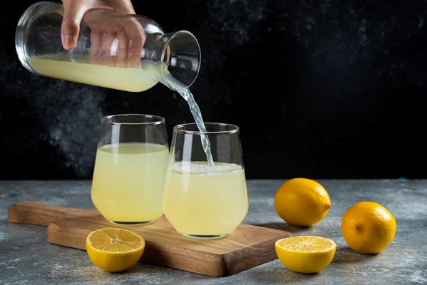a hand pouring lemon juice in a glass cup - Гранатовый безалкогольный глинтвейн с яблоком