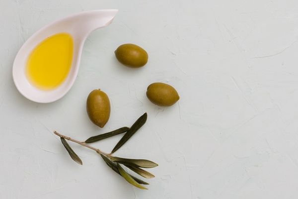 an overhead view of olive leaves and oil on white concrete background - Омлет со шпинатом