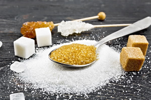 brown granulated sugar in a metal spoon white granulated sugar on a table - Безалкогольный яблочный глинтвейн с апельсином