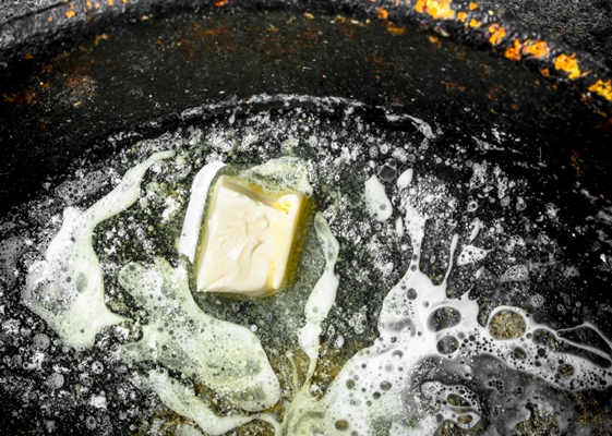 butter in an old pan on rustic background - Суп из брюссельской капусты со сметаной и сливочным маслом