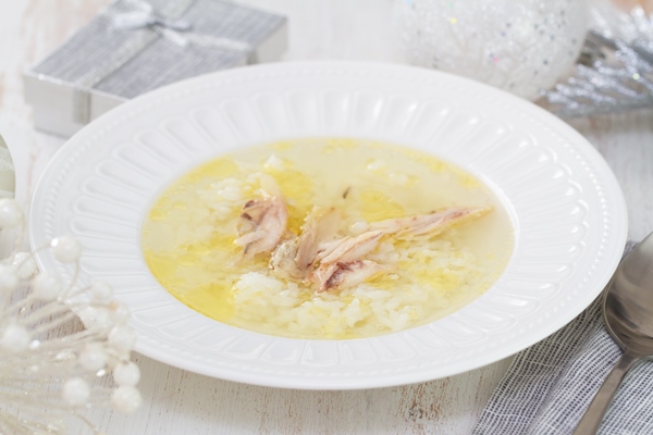 chicken broth with rice and chicken in white dish on white wood - Бульон с рисом