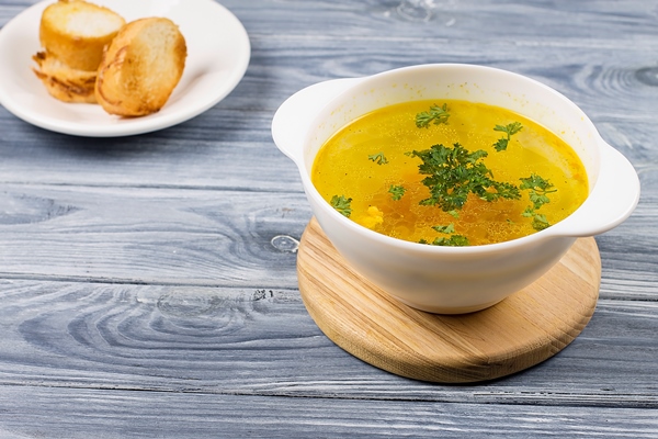 chicken soup in a white plate with bread on a wooden background - Правила приготовления прозрачных супов