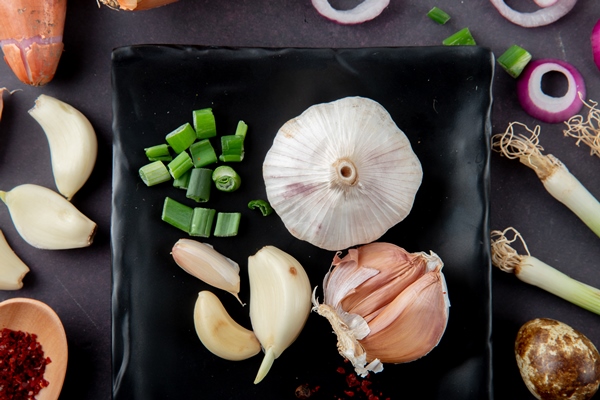 close up view of vegetables as garlic bulb and cloves cut scallion egg onion slice on maroon background - Фаршированные яйца с крабовыми палочками