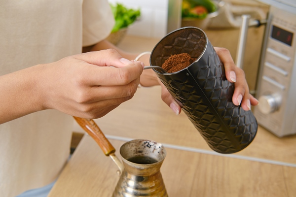 closeup view of hands making ground coffee at home in turkish cezve - Кофе по-арабски