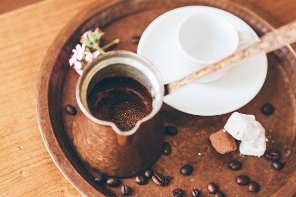 coffee in a brown coffee copper and a white ceramic cup on a tray with coffee beans - Кофе с сахаром и солью в турке