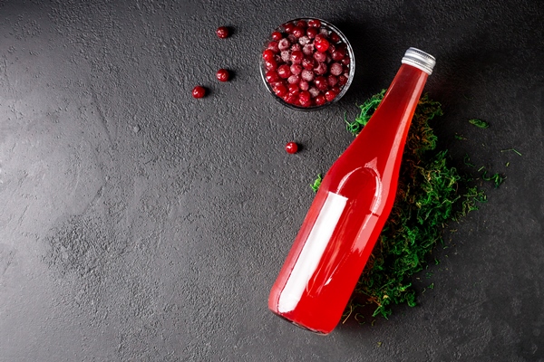 cranberry juice in a glass bottle on black stone background top view - Безалкогольный глинтвейн на смеси соков