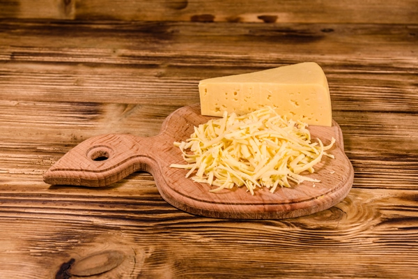 cutting board with grated cheese on wooden table - Фриттата с картофелем