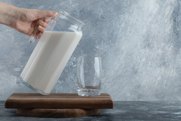 female hands holding jug of milk on marble - "Золотое" молоко