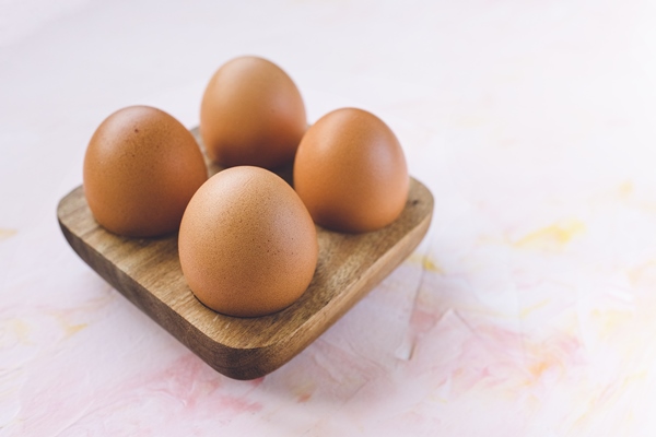 four brown eggs in a wooden storage organizer - Фриттата с макаронами, сыром и ветчиной