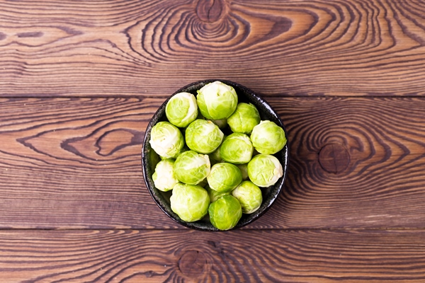 fresh brussels sprouts in a bowl on a black slate on a wooden table place for - Суп из брюссельской капусты со сметаной и сливочным маслом