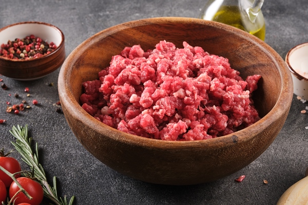 fresh raw mince minced beef ground meat with herbs and spices in wooden plate - Котлеты, фаршированные яйцом