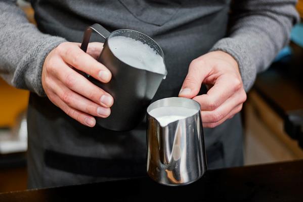 front view of male barista pouring milk foam in cups - Макиато