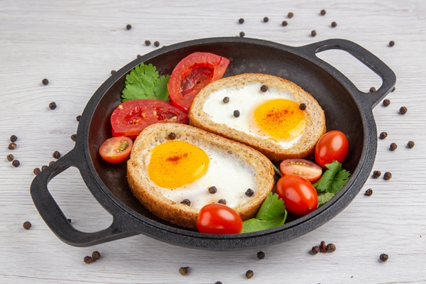 front view tasty egg toasts with tomatoes inside pan on white background breakfast lunch color salad food meal - Яйцо в хлебе