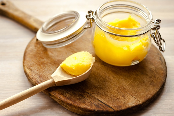 ghee clarified butter desi yellow color in glass jar wood spoon on wooden cutting board - Омлет-страта по-американски