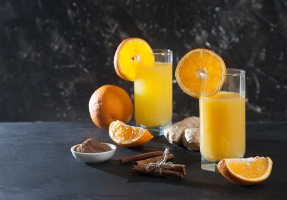 ginger orange drink in glass glasses orange ginger and cinnamon on a black background detox fresh juice - Безалкогольный апельсиновый глинтвейн с имбирём