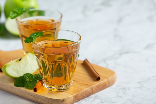 glasses of green apple healthy tea put next to fresh green apples - Безалкогольный яблочный глинтвейн с апельсином
