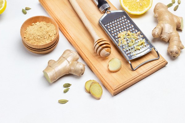 grater with grated ginger stick with honey on board ginger root dry ginger and lemon on table white background top view - Безалкогольный апельсиновый глинтвейн с имбирём