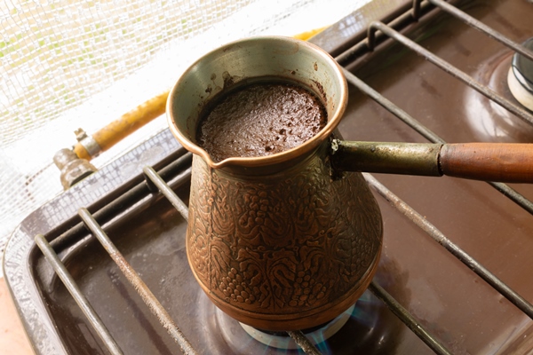 high angle shot of coffee is brewed in a copper turk on the gas stove - Американо