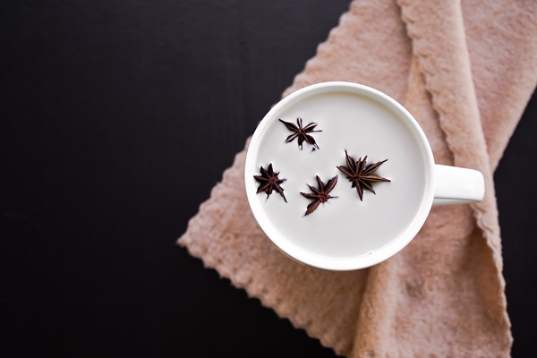 hot drink for autumn winter concept hot milk with star anise spice fruits in white cup on wooden table flat lay - Горячий шоколад