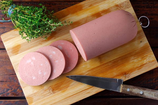 piece of whole raw pork mortadella on cutting board with some slices italian food - Запеканка из макарон