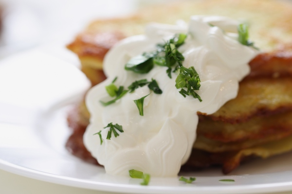 potato pancakes with sour cream and herbs on plate cooking healthy breakfast concept - Драники на сметане