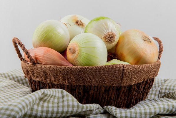 side view of onions in basket on plaid cloth on white background 1 - Бозбаш