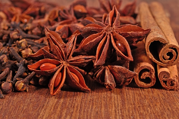 star anise cinnamon sticks and cloves on a wooden background - Безалкогольный глинтвейн с клюквой