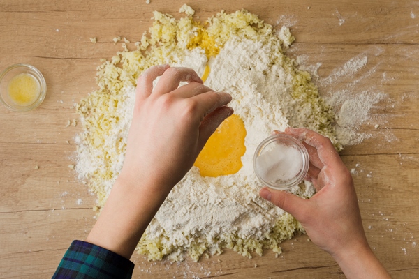 a person s hand adding the pinch of salt in the flour and grated cheese for preparing italian gnocchi on wooden desk - Суп молочный с картофельными клёцками