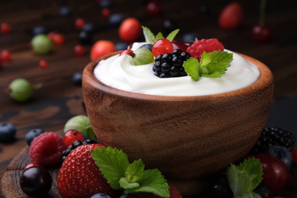 bowl of yogurt with wild berries on dark wooden table - Суп из клюквы и яблок со сметаной