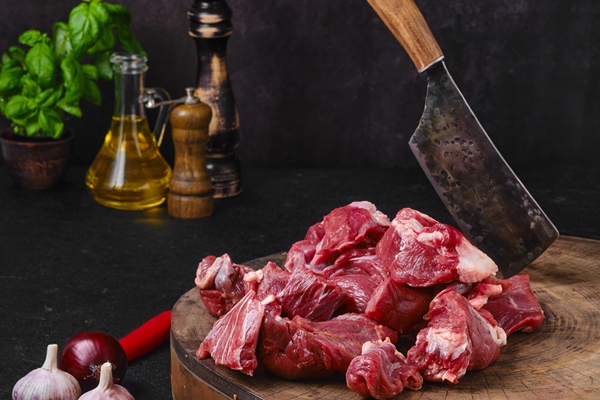 chopping fresh beef meat on wooden chopping stump - Рагу из баранины