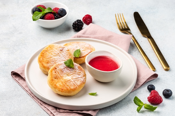 cottage cheese fritters or syrniki served with sauce and berries top view ukrainian russian food - Творожники ванильные со сметаной