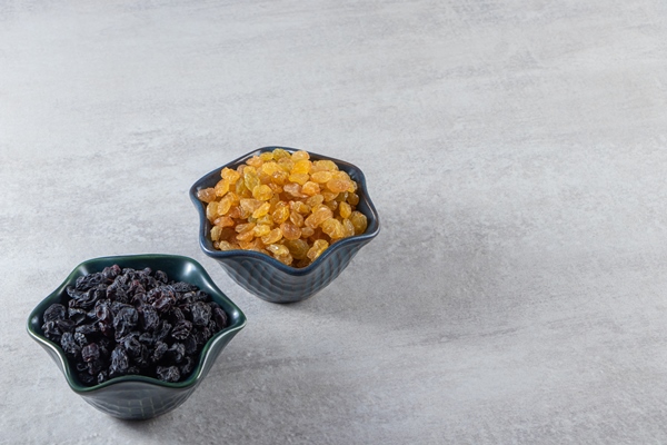 dark bowls with dried golden and black raisins on stone background - Язык отварной под соусом
