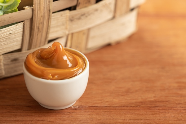 dulce de leche in a white container on a wooden table - Карамельно-медовый соус