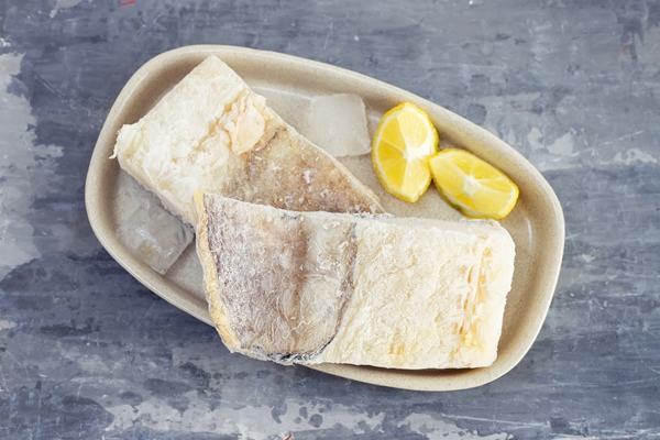 frozen raw cod fish with ice on dish on ceramic - Салат из картофеля и трески с хреном