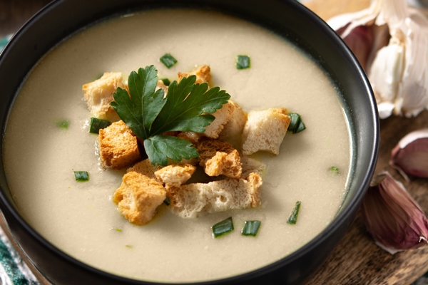 garlic soup topped with croutons in bowl on wooden table - Рисовый суп-пюре