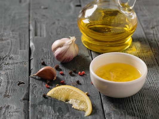 olive oil with garlic and lemon and chili pepper in a white bowl on a gray table dressing for diet salad - Постный соус с каперсами