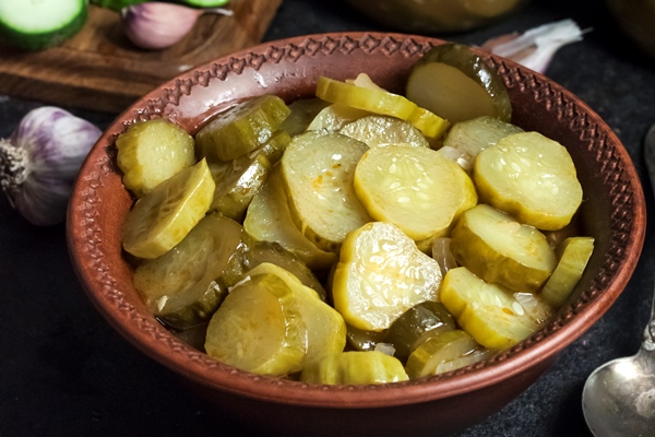 pickled cucumber salad in a bowl and jars on black background - Винегрет с консервированным мясом