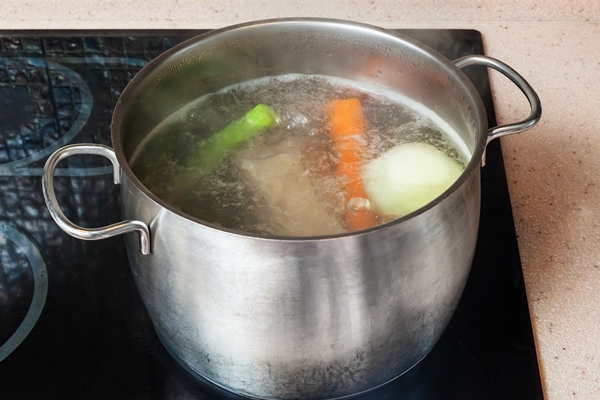 simmering meat stock in stockpot on ceramic cooker - Язык отварной под соусом