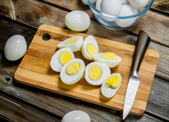 sliced boiled eggs on cutting board - Салат из крабовых палочек с ананасами и сыром
