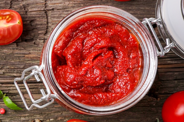 spicy rich tomato sauce in glass jar with red tomatoes and seasonings on wooden - Мясной гуляш